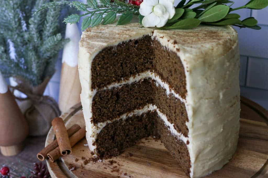 fresh milled gingerbread cake with cream cheese icing that has been sliced with cinnamon sticks 