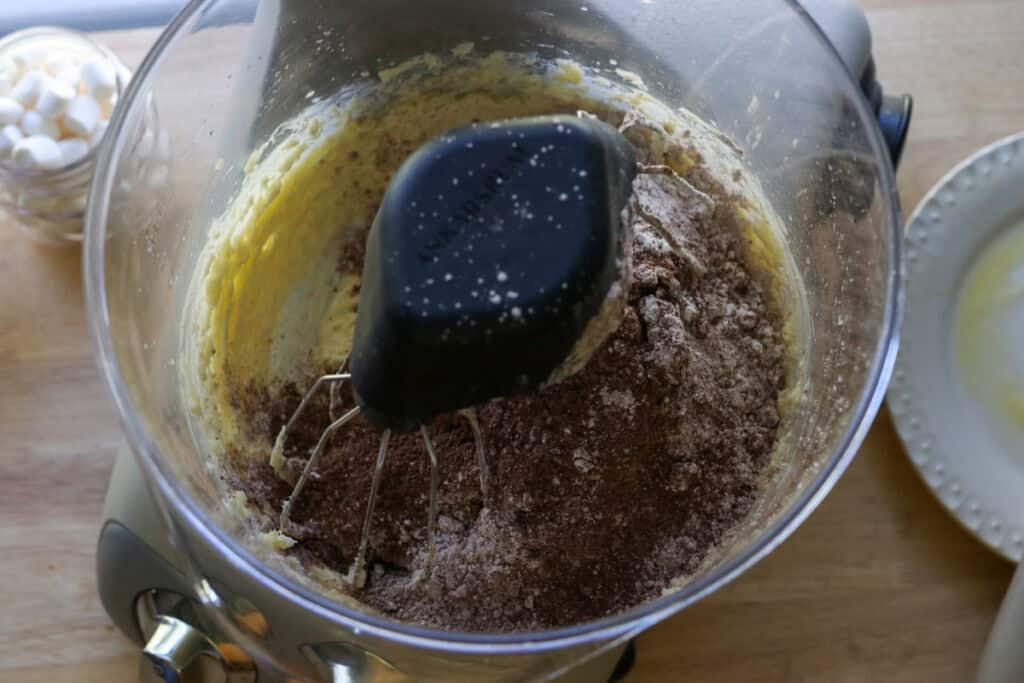 powdered sugar and cocoa powder in a mixing bowl to make chocolate buttercream for Fresh Milled Hot Cocoa Cupcakes with Ganache Filling