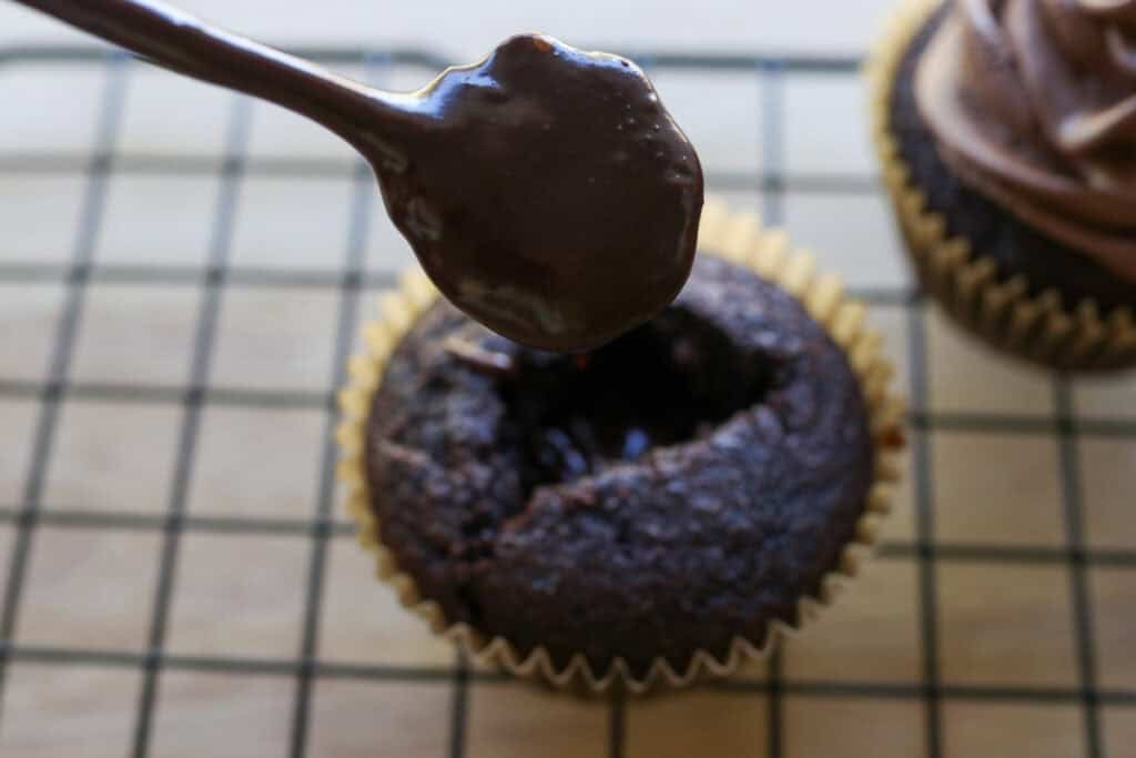 putting chocolate ganache filling in fresh milled hot cocoa cupcakes