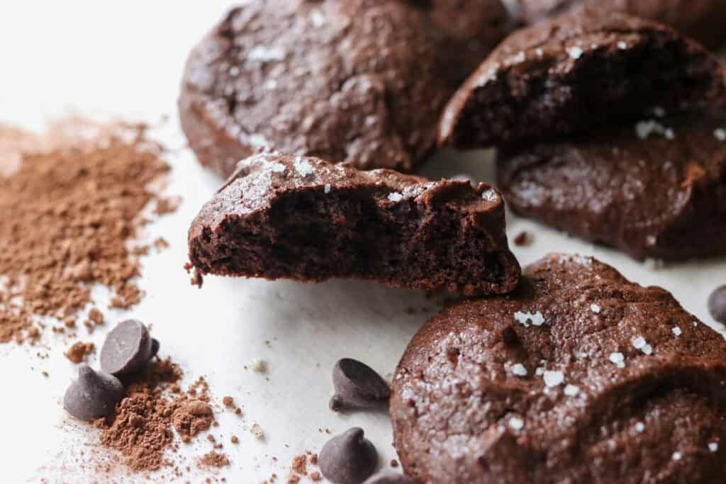 Delicious Brownie Cookies cut in half with Freshly Milled Flour and cocoa powder on a white background