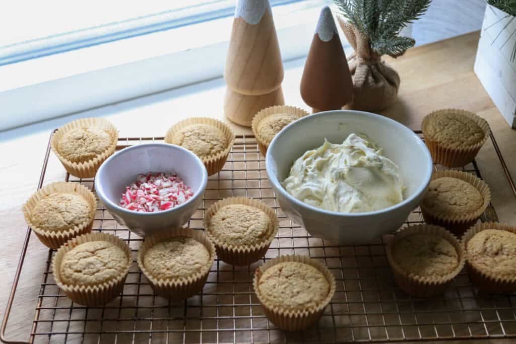 Freshly Milled White Chocolate Peppermint Cupcakes cooling on a wire rack with buttercream in a bowl