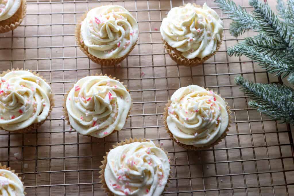 Freshly Milled White Chocolate Peppermint Cupcakes on a wire rack with greenery