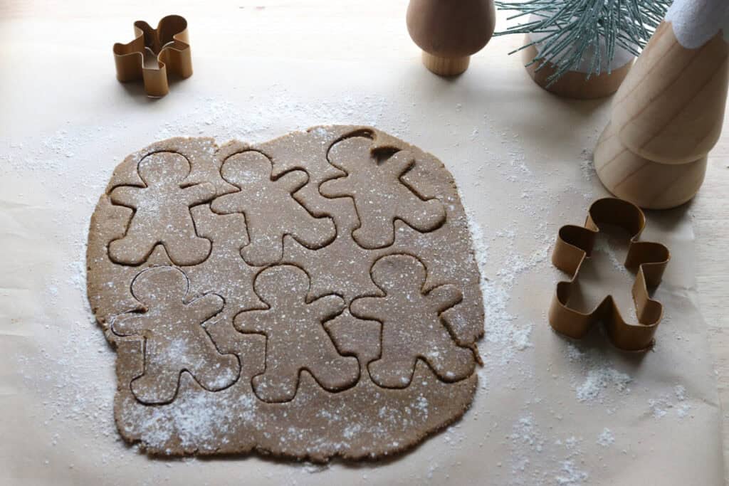 fresh milled gingerbread dough that has been rolled out and cut into gingerbread shapes