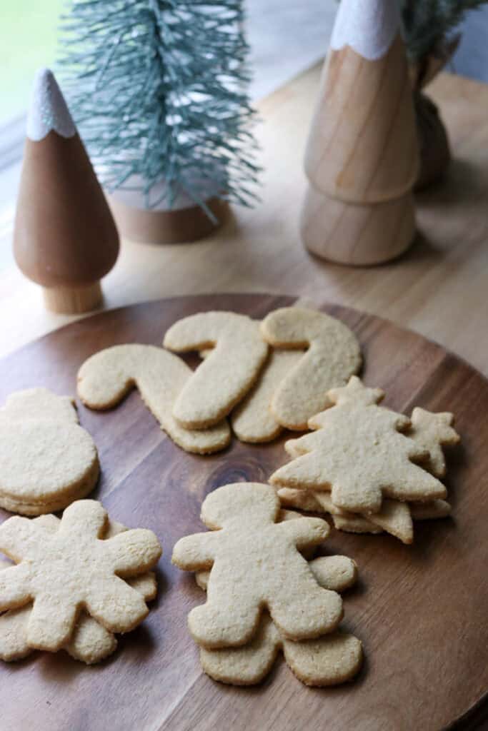 The Best Fresh Milled Healthy Christmas Sugar Cookies on a wooden tray with christmas trees behind it