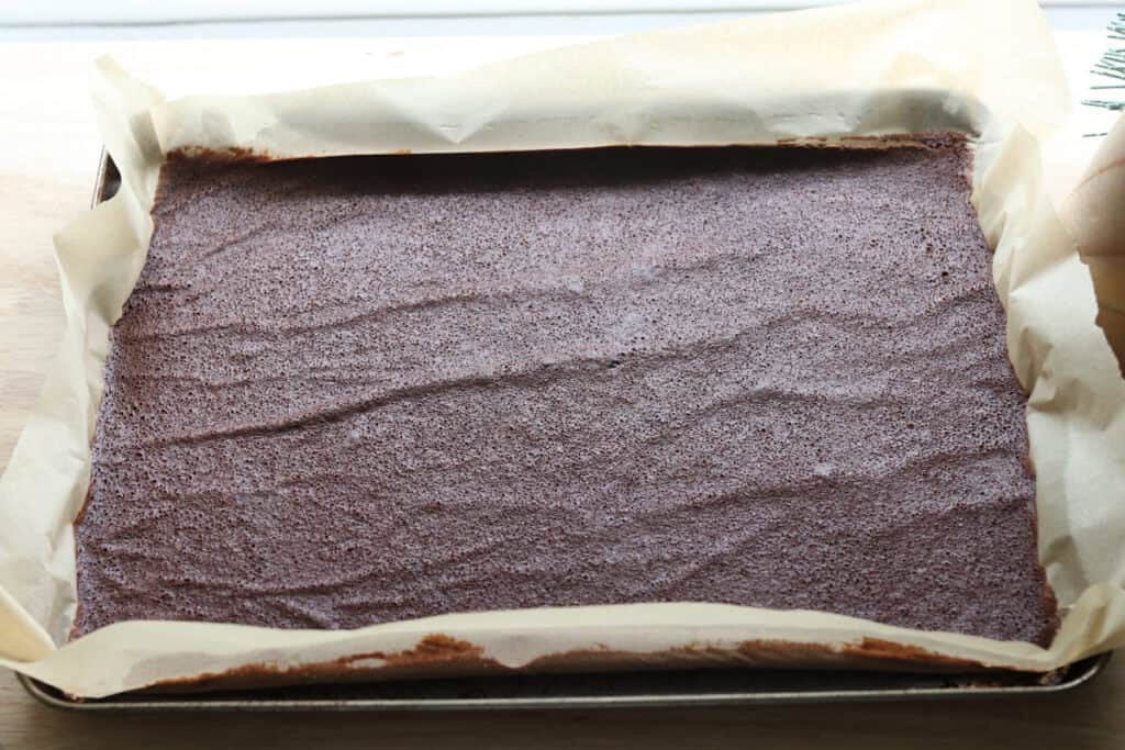 freshly milled chocolate yule log cake in a sheet pan that has been baked