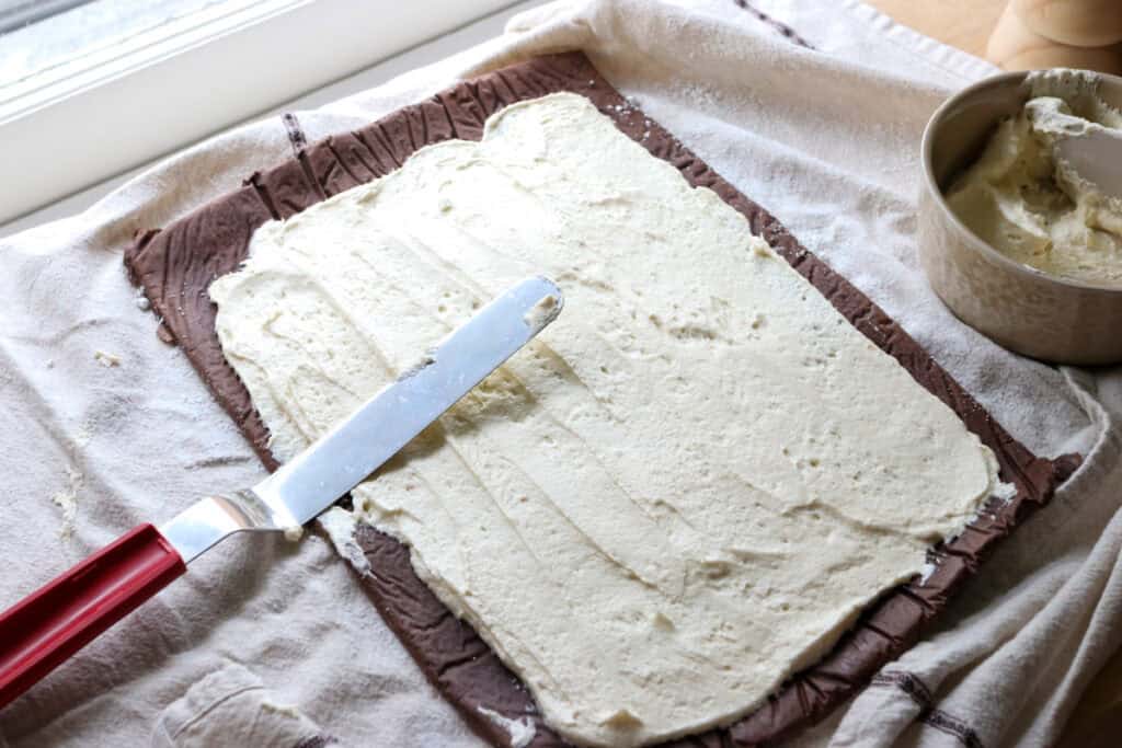  freshly milled chocolate yule log cake with whipped cream filling spread on it