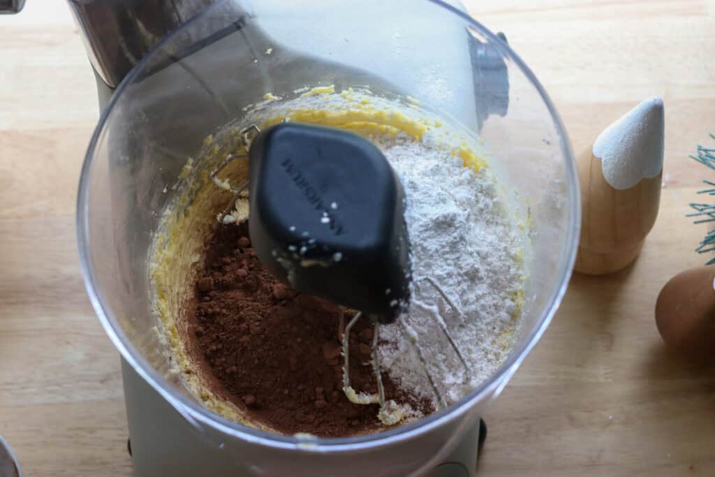 powdered sugar and cocoa powder in a mixing bowl to make chocolate buttercream for the freshly milled chocolate yule log cake
