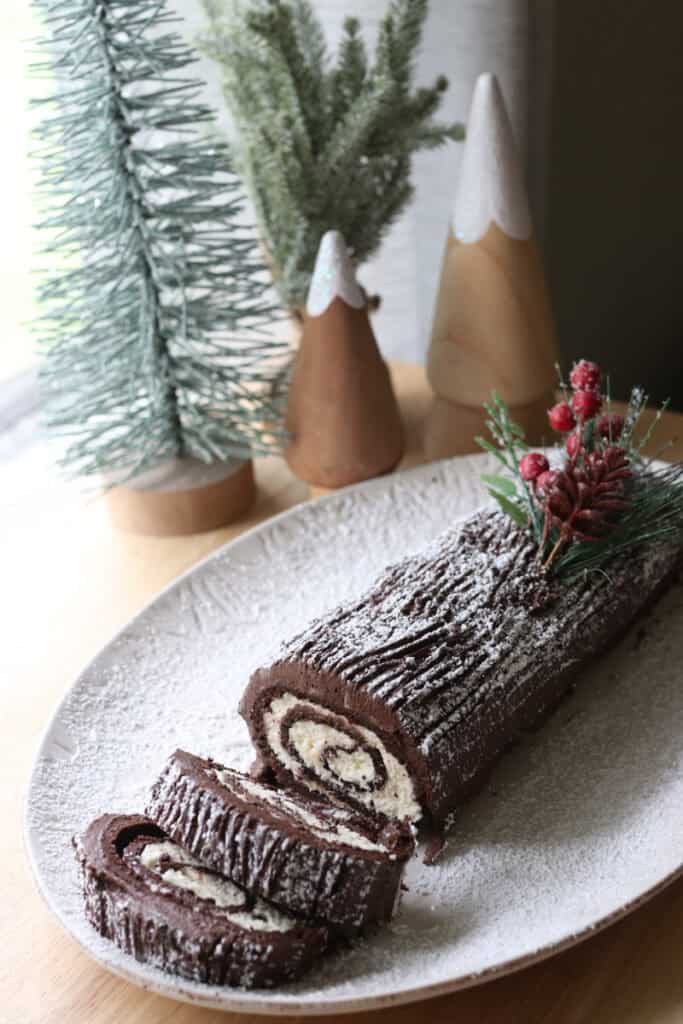 freshly milled chocolate yule log cake cut into slices on a white plate