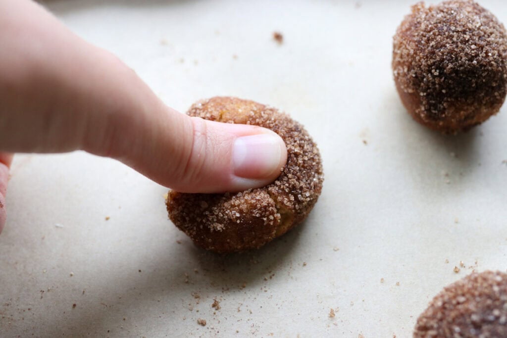 fresh milled eggnog snickerdoodle thumbprint cookie dough balls being pressed down in the center