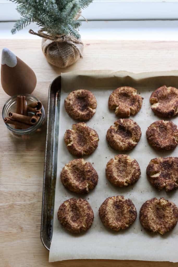 fresh milled eggnog snickerdoodle thumbprint cookies on a baking sheet with parchment