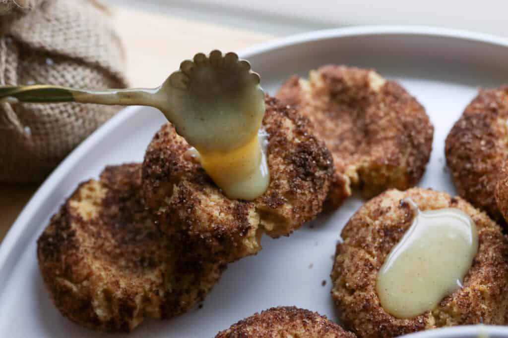 spooning eggnog filling into the center of a fresh milled eggnog snickerdoodle thumbprint cookie