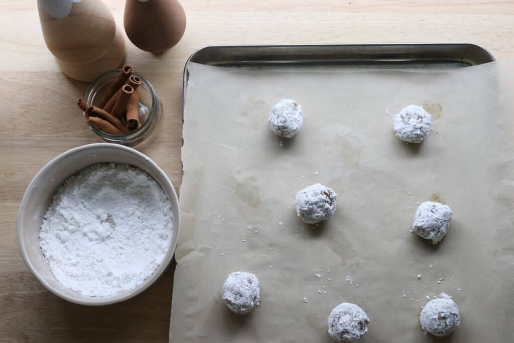freshly milled gingerbread crinkle cookie dough rolled in powdered sugar and placed on a baking sheet