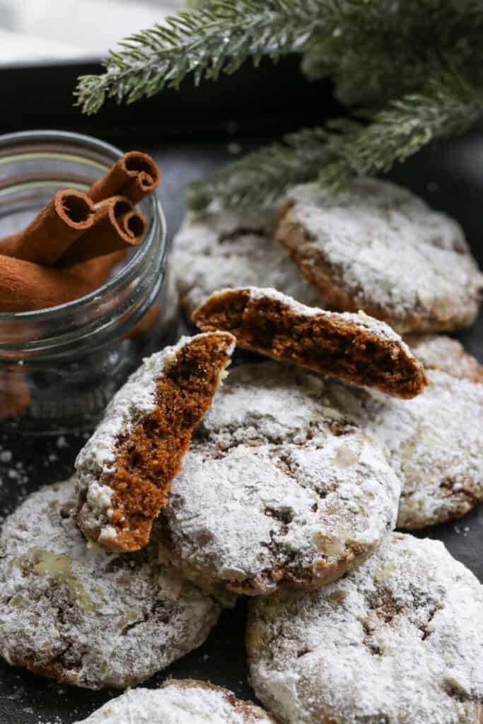 freshly milled gingerbread crinkle cookies with one cut in half and cinnamon sticks in a jar