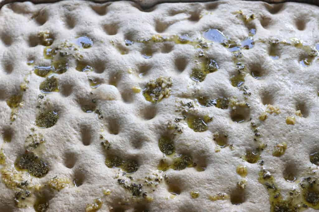 Easy Garlic Herb Focaccia dough with garlic oil on top of it