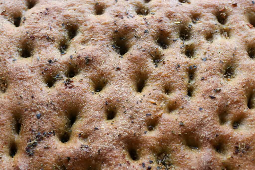 fresh milled focaccia covered with garlic and herbs and holes poked in it