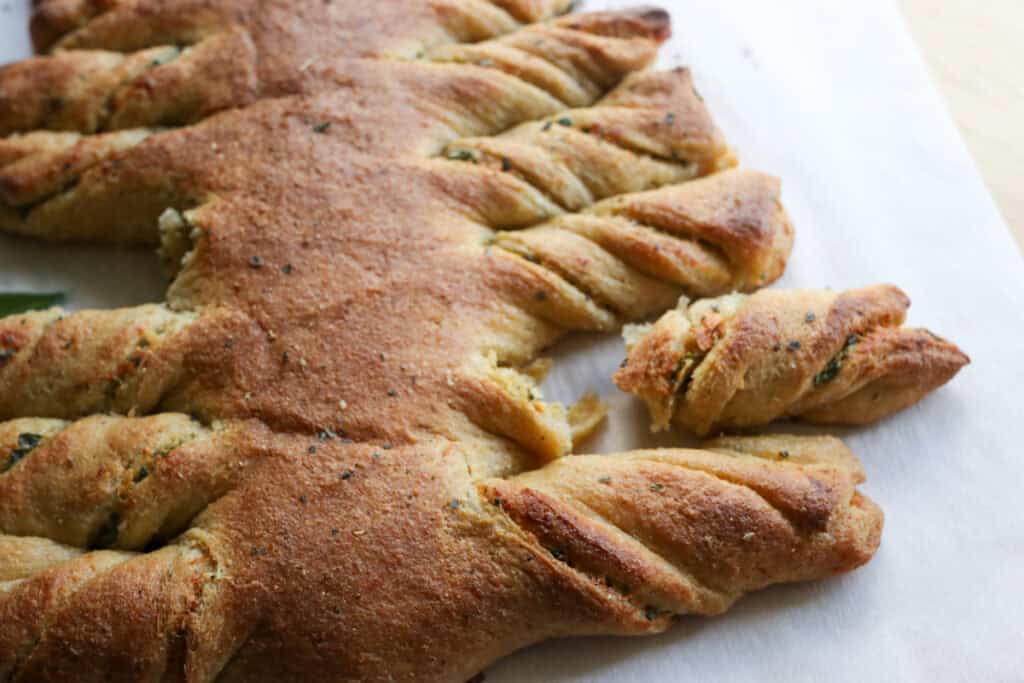 Fresh Milled Christmas Tree Garlic and Herb Bread on white parchment paper with a branch torn off