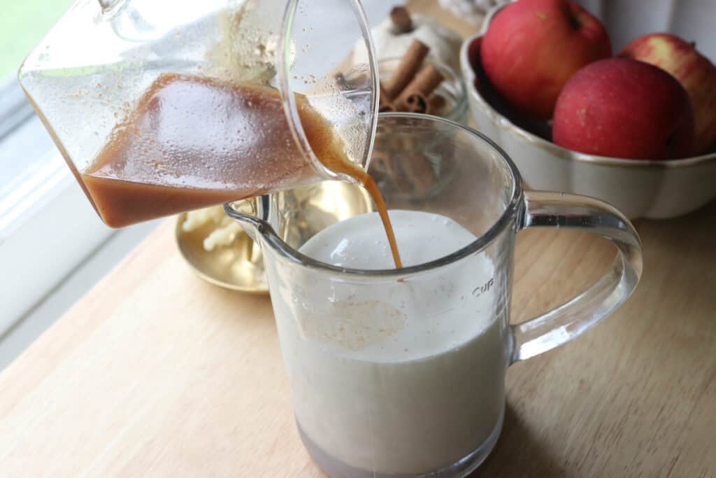 pouring apple cider into a measuring cup to make Delicious Homemade Apple Flavored Coffee Creamer