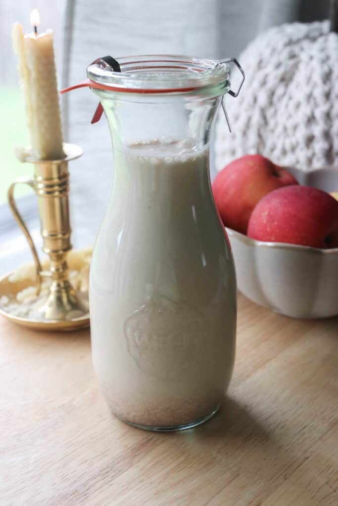 Delicious Homemade Apple Flavored Coffee Creamer in a jar with a glass lid and a candle behind it