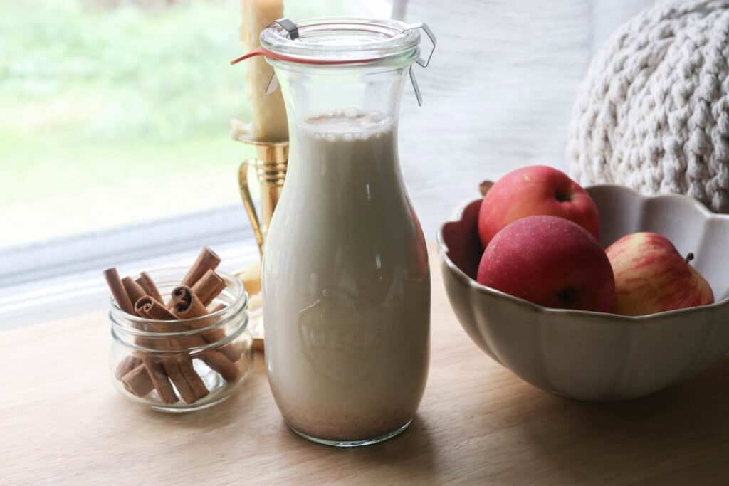 Delicious Homemade Apple Flavored Coffee Creamer in a glass pitcher and apples in a bowl