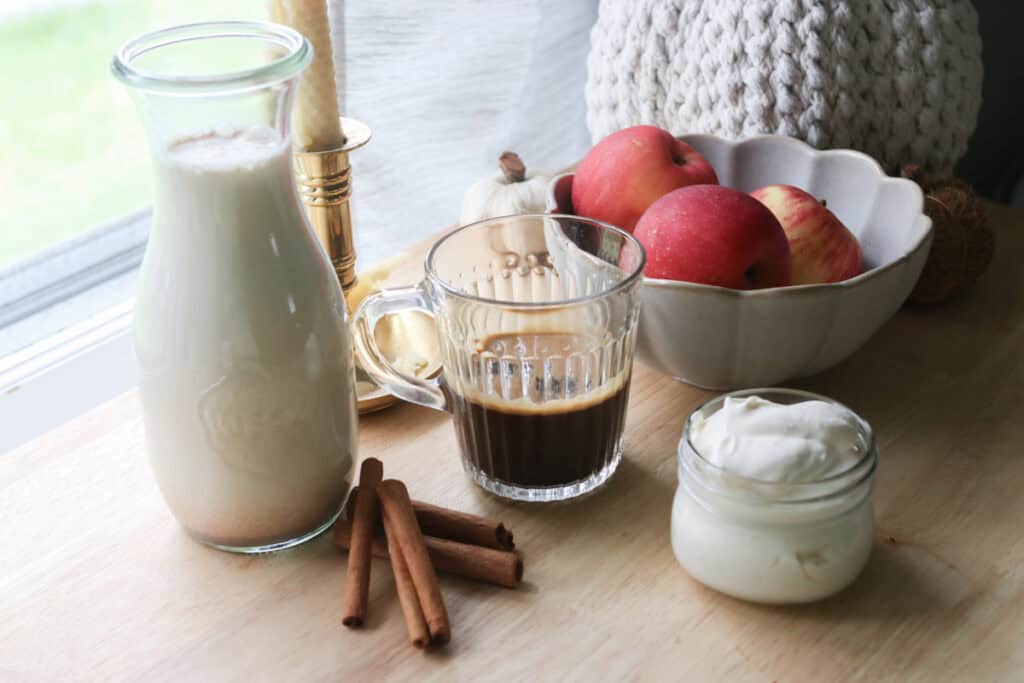 Delicious Homemade Apple Flavored Coffee Creamer in a jar and coffee and whipped cream and cinnamon sticks
