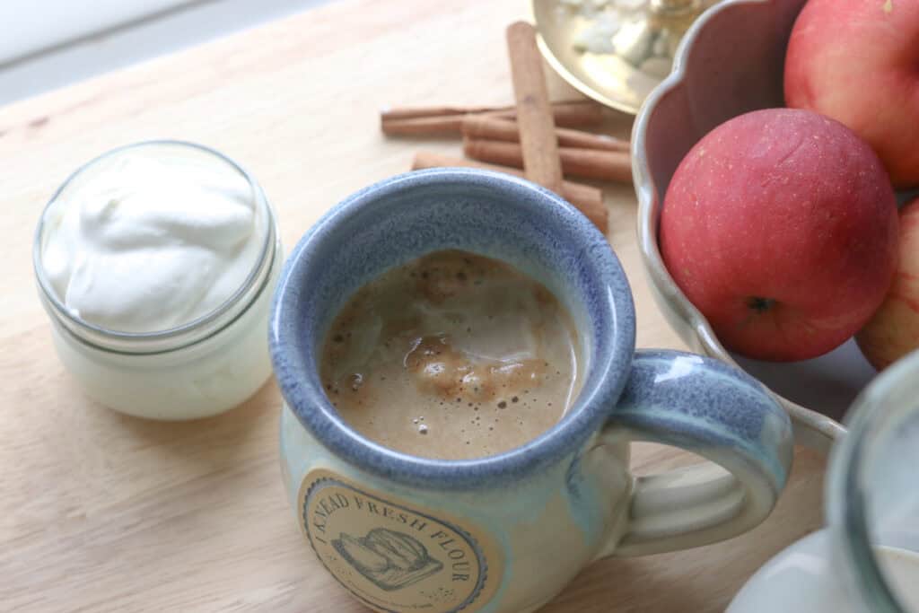 coffee and Delicious Homemade Apple Flavored Coffee Creamer in a mug with whipped cream in a jar and apples