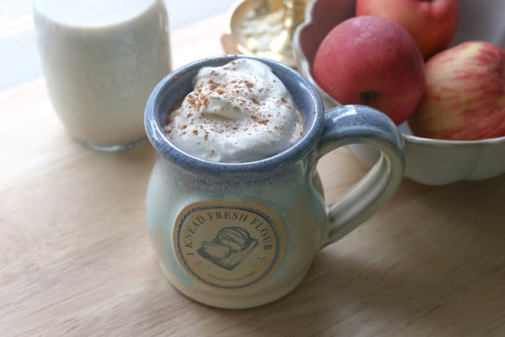 Delicious Homemade Apple Flavored Coffee Creamer in a mug with coffee and apples in a bowl