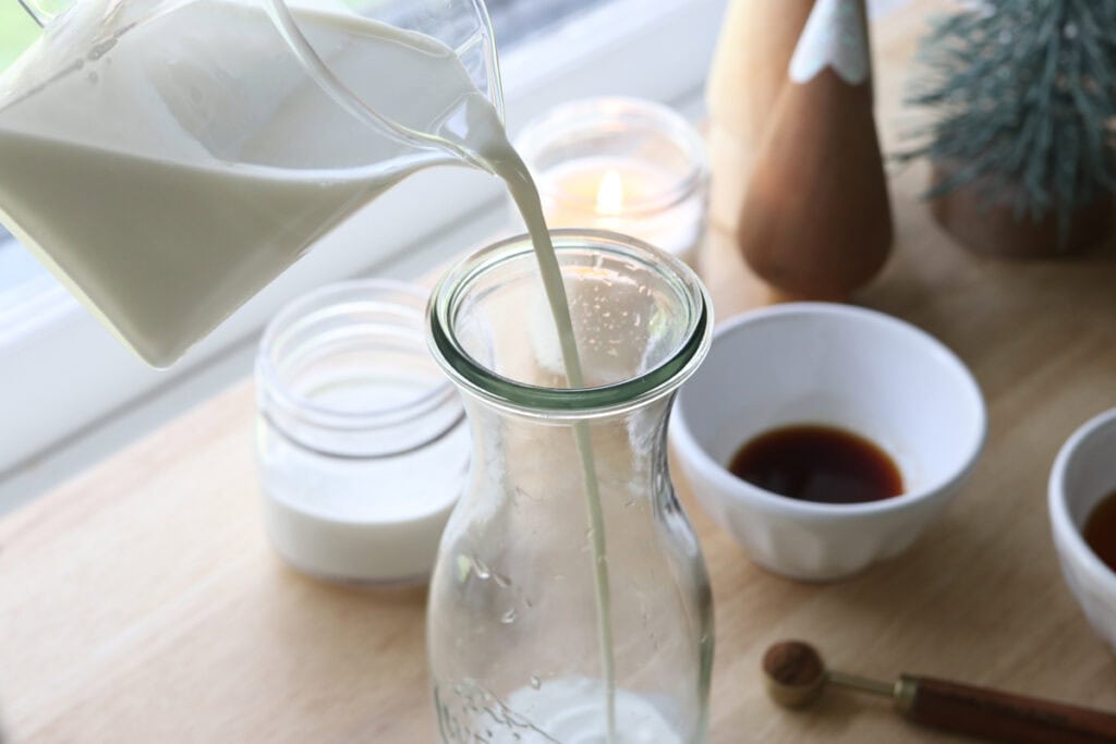 pouring milk into a glass jar to make Delicious Healthier Teddy Graham Coffee Creamer