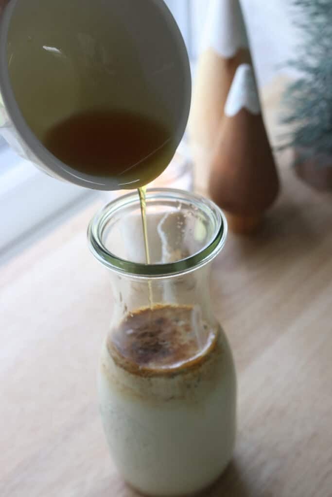 pouring maple syrup in a glass to make Delicious Healthier Teddy Graham Coffee Creamer
