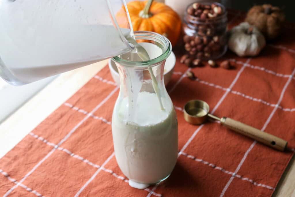 pouring half and half into a pitcher to make naturally sweetened hazelnut coffee creamer