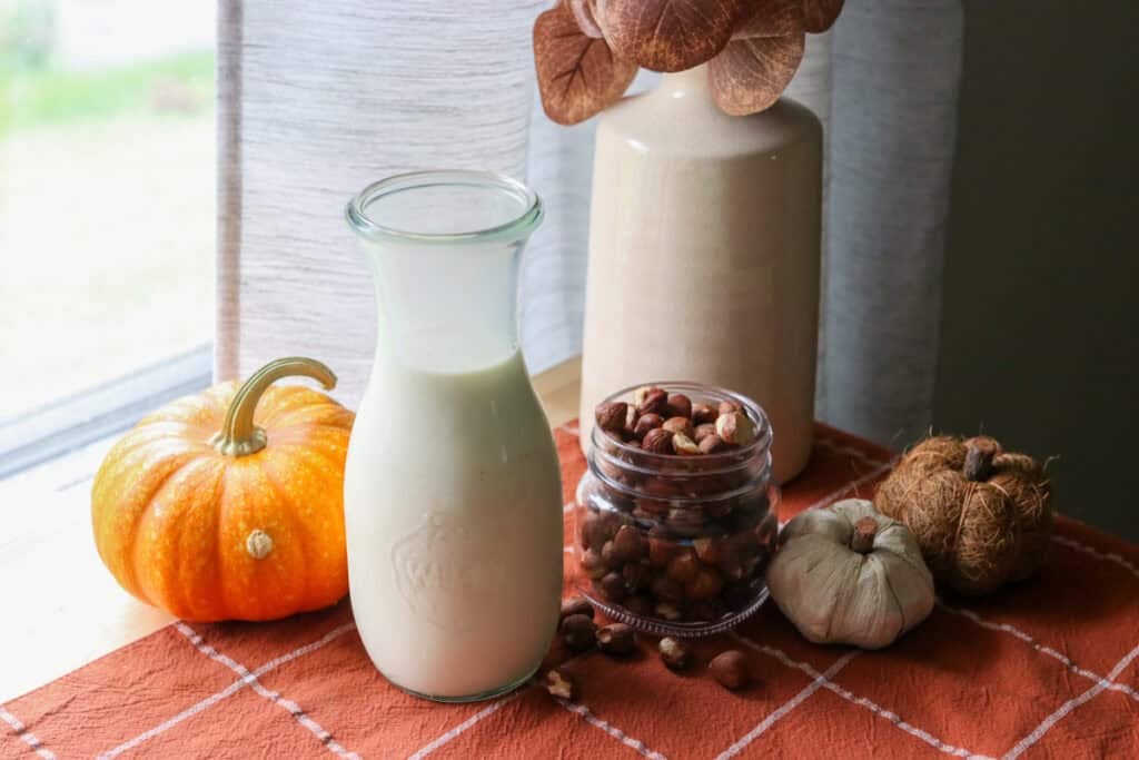 naturally sweetened hazelnut coffee creamer in a glass pitcher with hazelnuts in a glass jar