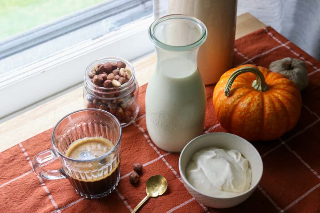 naturally sweetened hazelnut coffee creamer, whipped cream, coffee and a gold spoon