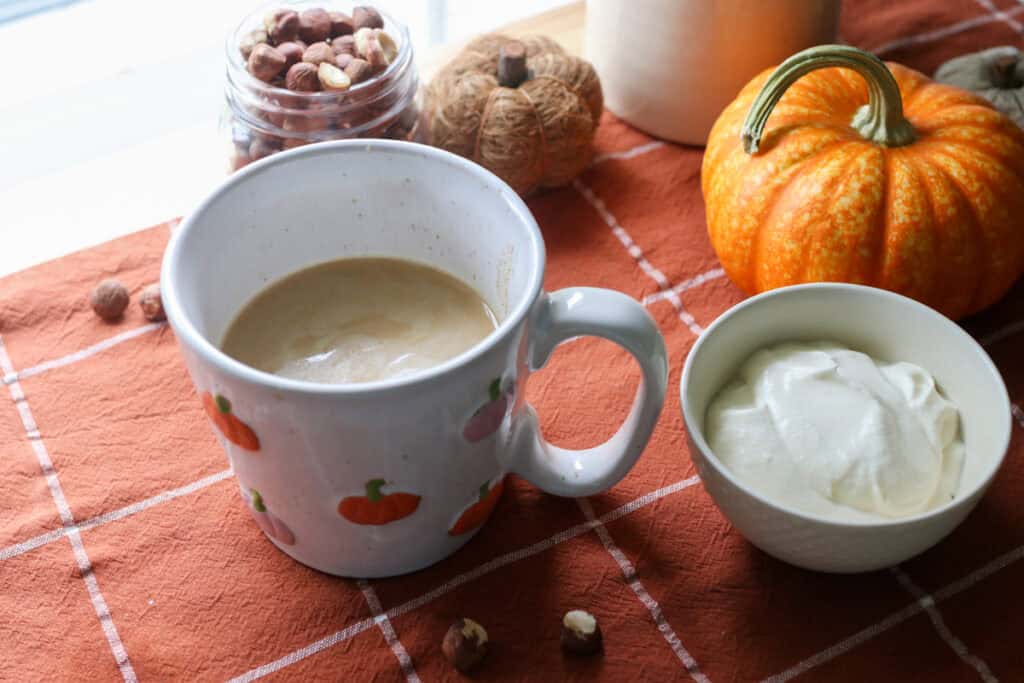 coffee and naturally sweetened hazelnut coffee creamer in a white mug with pumpkins on it