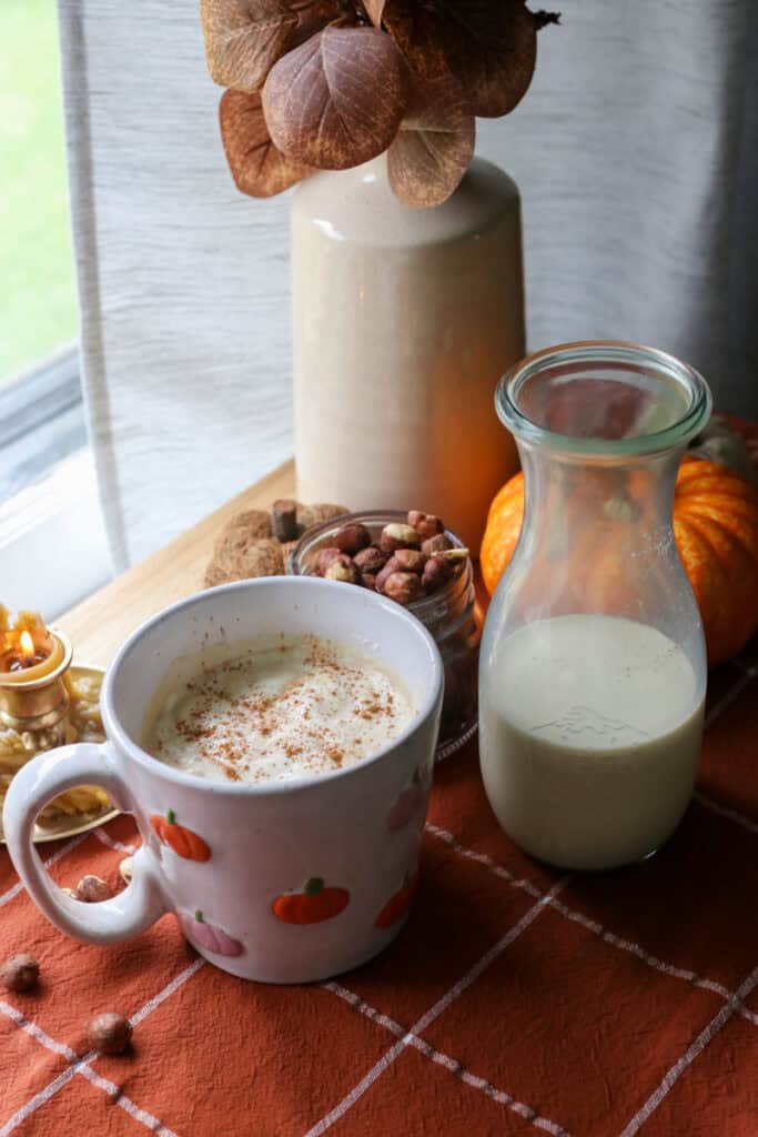 naturally sweetened hazelnut coffee creamer in a jar with a mug full of coffee beside it