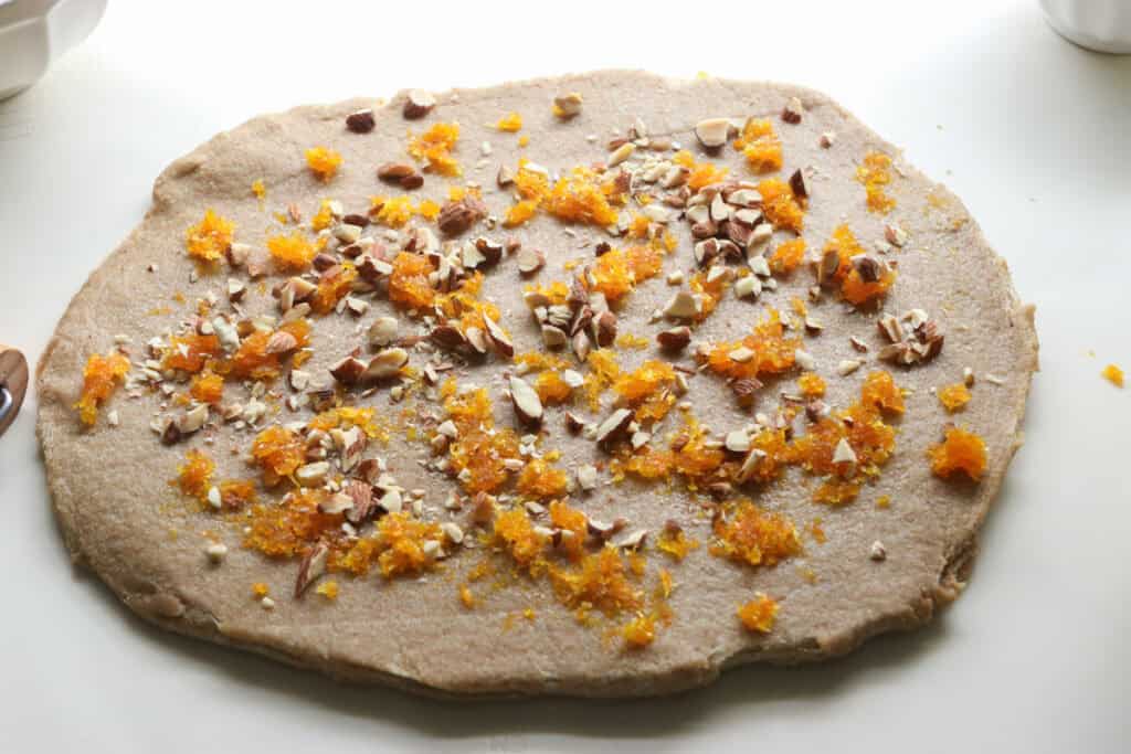 fresh milled Christmas Stollen bread rolled into an oval with orange zest and almonds on it