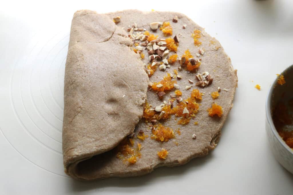 fresh milled Christmas Stollen dough filled with zest and nuts and folded in half