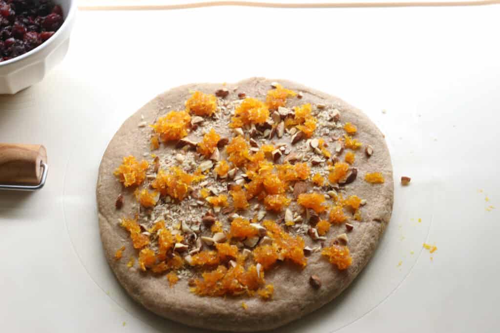 fresh milled Christmas Stollen dough rolled out with orange zest and almonds on it