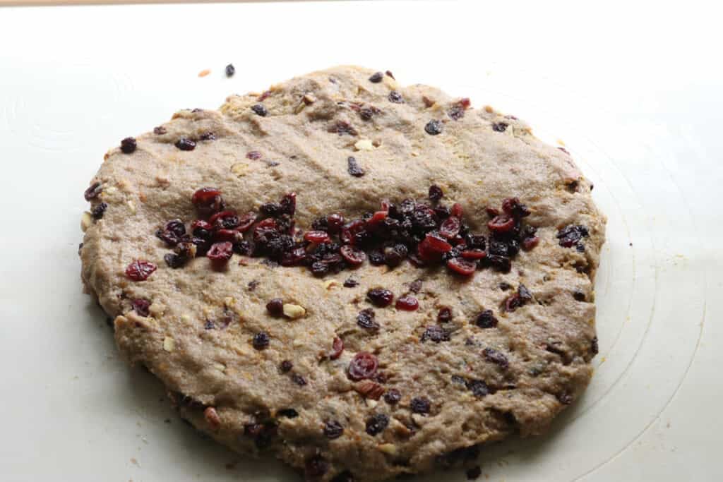 fresh milled Christmas Stollen dough with cranberries and currants filled in the middle of it