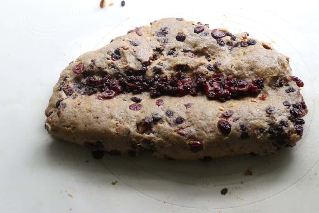 fresh milled Christmas Stollen dough folded in half and filled with dried fruits on a mat