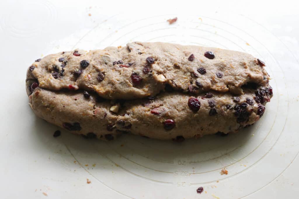 fresh milled Christmas Stollen dough on a mat with cranberries and currants and orange zest in it
