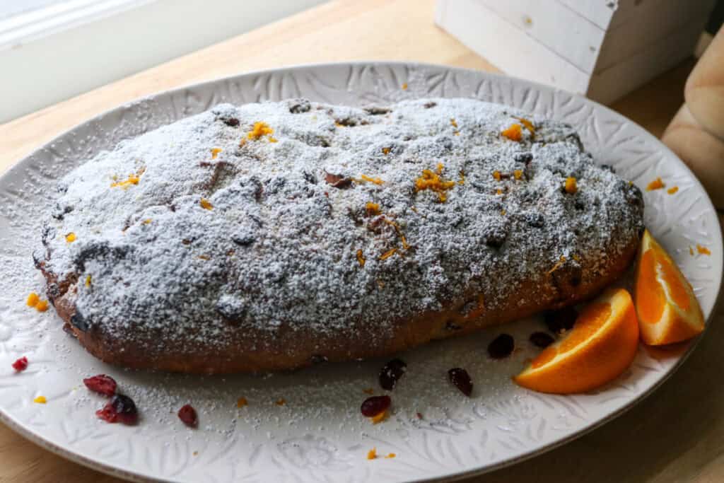 fresh milled Christmas Stollen bread on white plate covered in powdered sugar