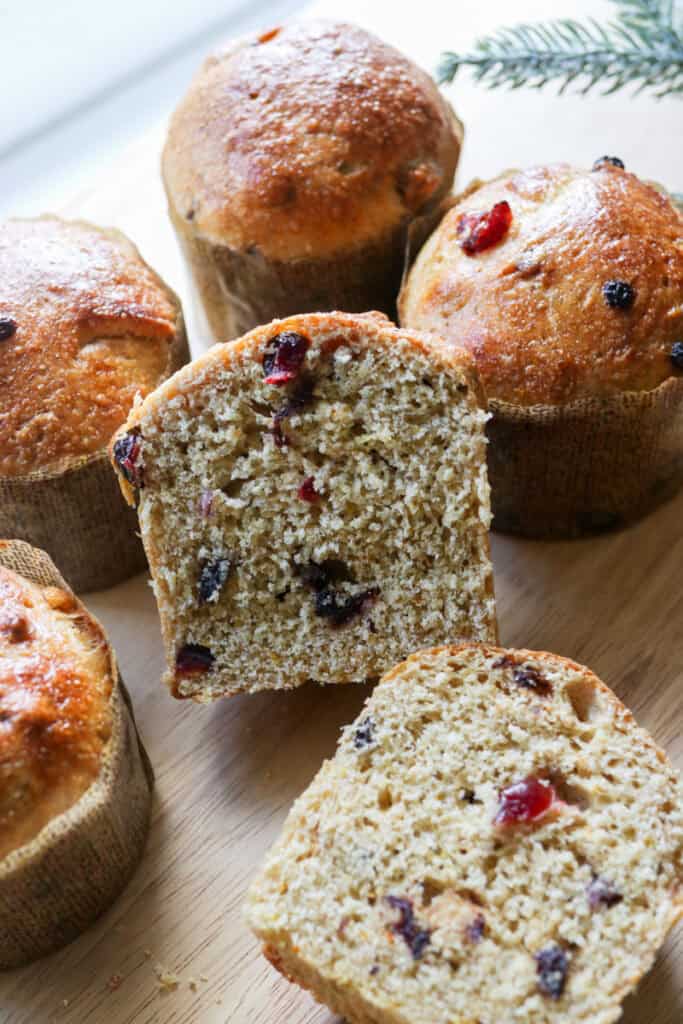 fresh milled mini panettone cut in half with dried fruit inside of it on a wooden board