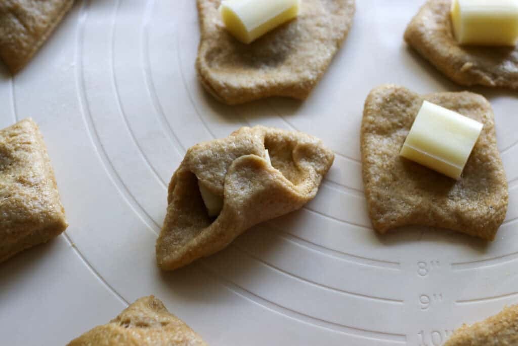 pieces of cheesy pull-apart Christmas tree bread with mozzarella sticks on a pastry mat