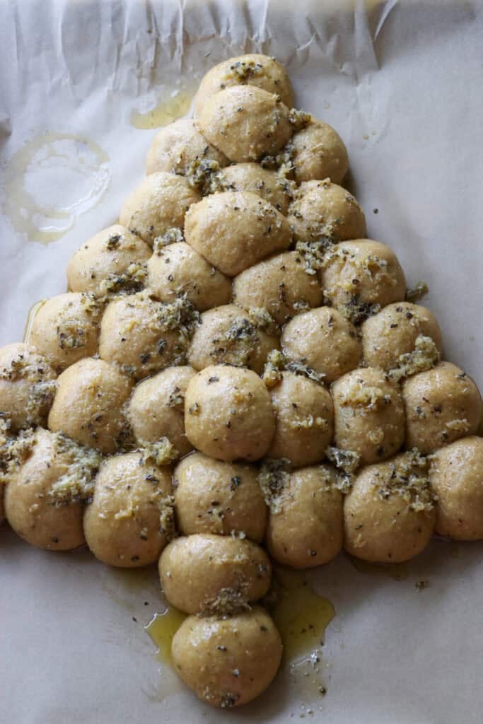Fresh Milled Cheesy Pull-Apart Christmas Tree Bread on parchment paper that is covered in garlic butter and herbs