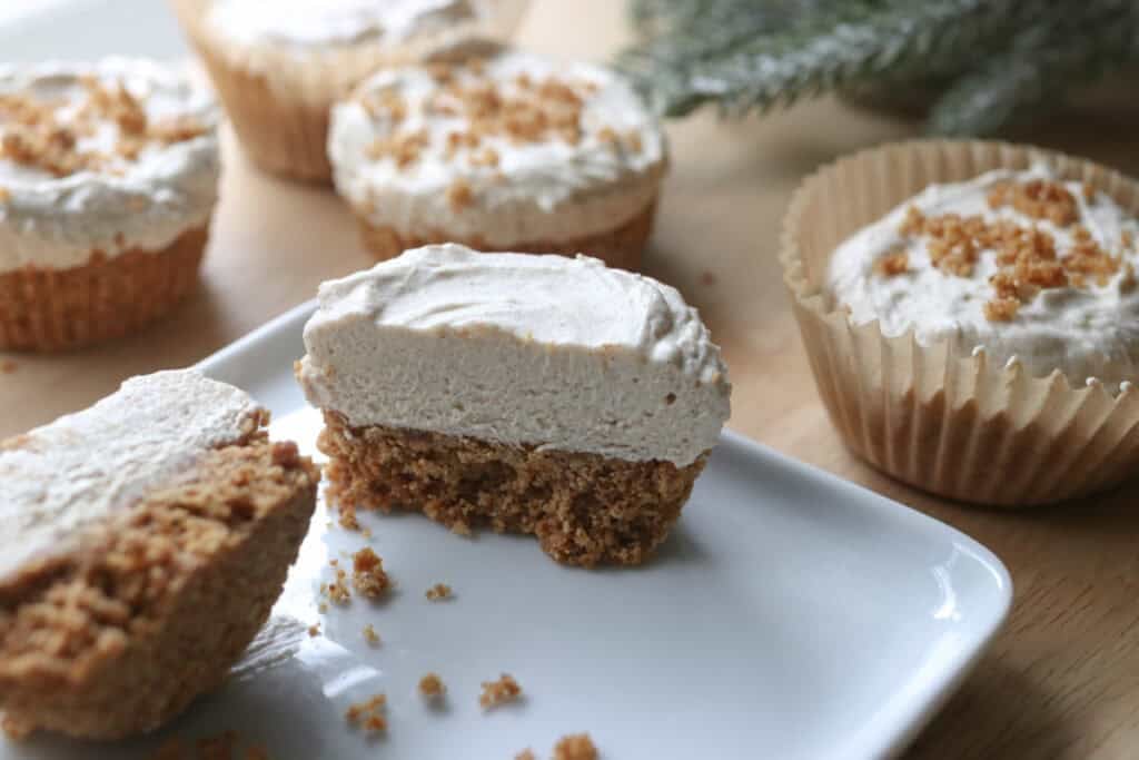 a No-Bake Mini Christmas Gingerbread Cheesecake Cup cut in half on a white plate