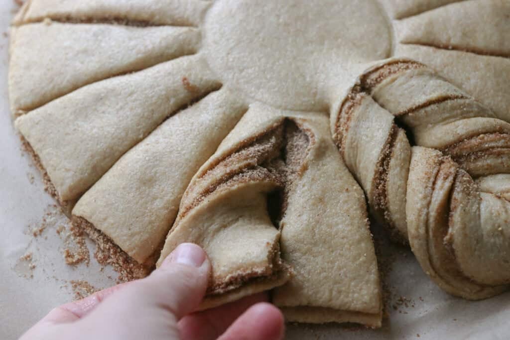 someone twisting a piece of fresh milled cinnamon sugar star bread