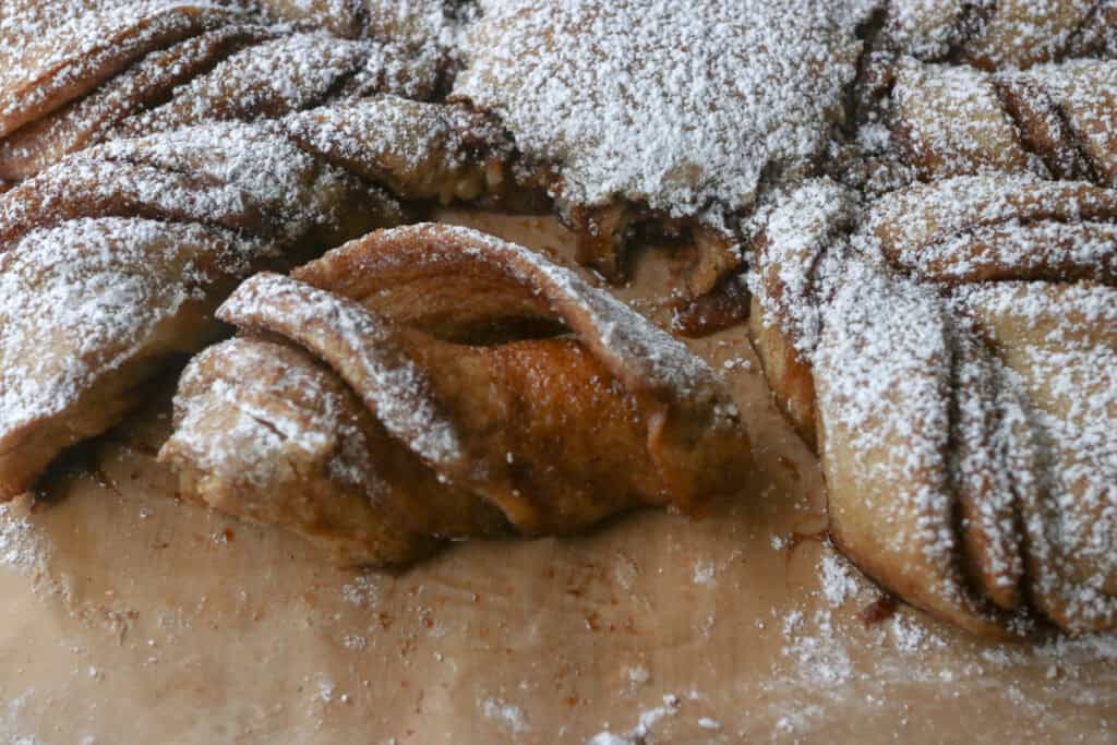 a piece of fresh milled cinnamon sugar star bread covered in powdered sugar