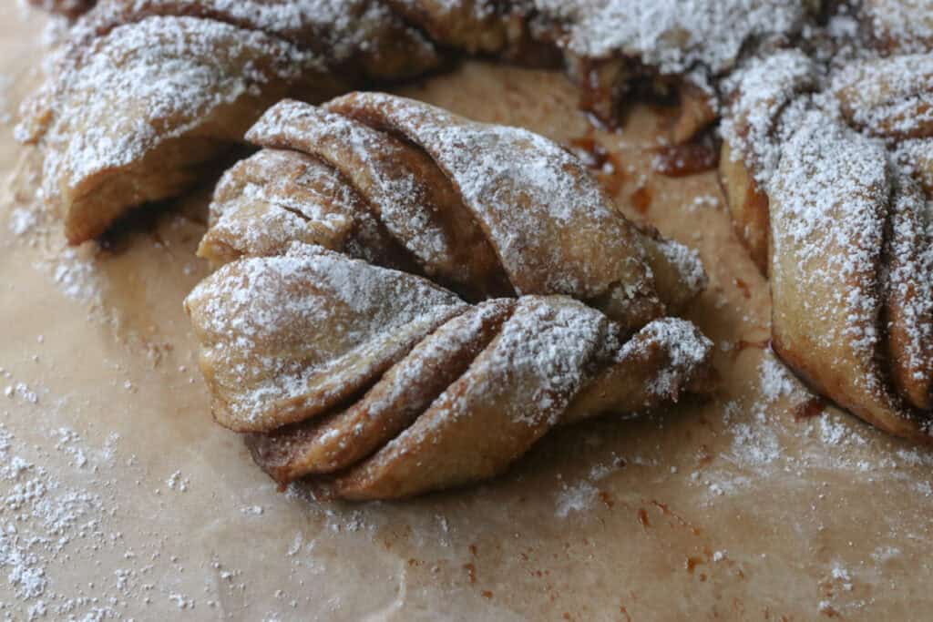 a piece of fresh milled cinnamon sugar star bread with powdered sugar on it