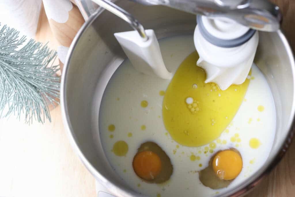 milk, oil, and eggs in a mixing bowl to make fresh milled fluffy Christmas dinner rolls