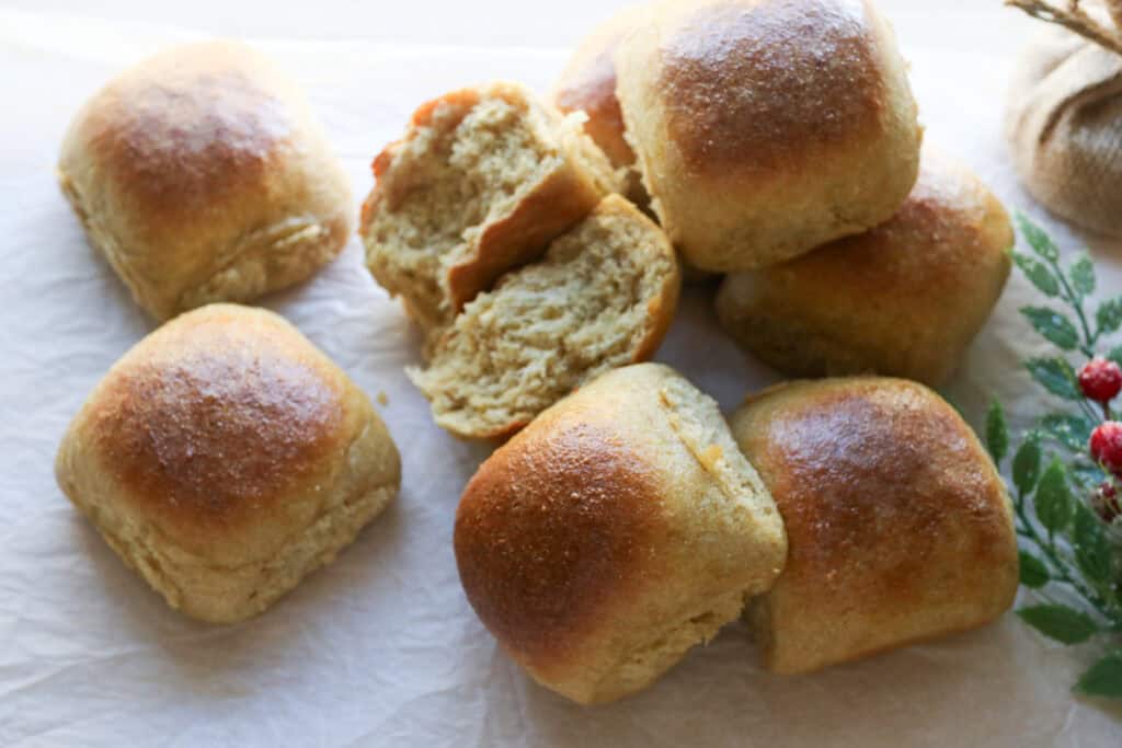 fresh milled fluffy Christmas dinner rolls on white parchment with one torn in half