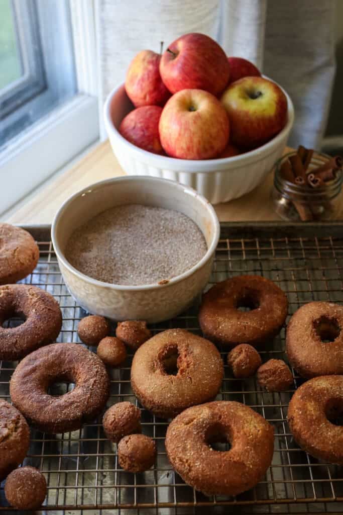 fresh milled apple cider donuts that have been fried and cooling on a wire rack